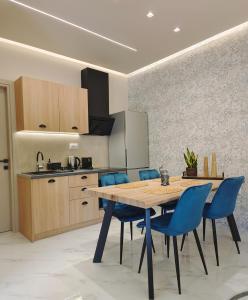 une cuisine avec une table en bois et des chaises bleues dans l'établissement Volos Guesthouse Chrysa, à Vólos