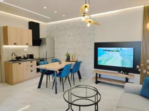 a kitchen and living room with a table and blue chairs at Volos Guesthouse Chrysa in Volos