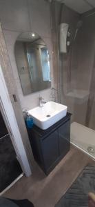 a bathroom with a sink and a mirror and a shower at Luton Lodge - Near London Luton Airport Luxury Quite Rooms Close to Restaurants & Shops in Luton