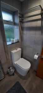 a white toilet in a bathroom with a window at Luton Lodge - Near London Luton Airport Luxury Quite Rooms Close to Restaurants & Shops in Luton