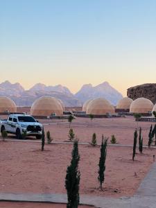Um SUV branco estacionado num deserto com cúpulas. em Princess luxury camp em Wadi Rum