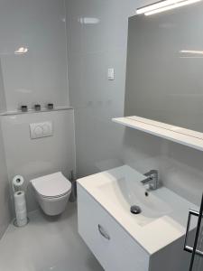 a white bathroom with a toilet and a sink at Apartment White Zagreb - private parking&garage in Zagreb