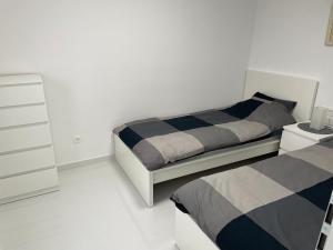 a white bedroom with two beds and a dresser at Apartment White Zagreb - private parking&garage in Zagreb