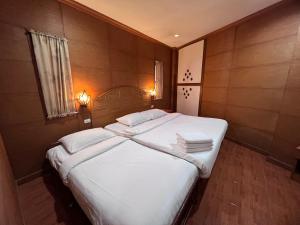 um quarto com uma cama com lençóis brancos e almofadas em Nanai 2 Residence Patong Phuket em Praia de Patong