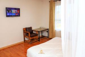 Cette chambre comprend un lit, un bureau et une chaise. dans l'établissement TAWALA GARDEN HOTEL, à Nairobi