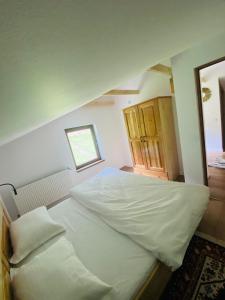 a large white bed in a room with a window at Hirsch Chalet Apuseni in Mărgău