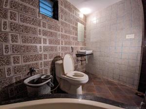 a bathroom with a toilet and a sink and a tub at KRL Inn in Mandvi