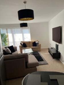 a living room with a couch and a flat screen tv at Spacious 2 bedroom Flat opposite COOP Live n Etihad Stadium in Manchester