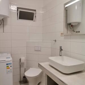 a white bathroom with a sink and a toilet at Apartments Tinjarosa in Mundanije