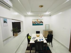 a dining room with a table and chairs and a painting at Abuja Getaways in Abuja