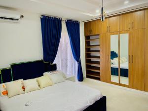 a bedroom with a large bed with blue curtains at Abuja Getaways in Abuja