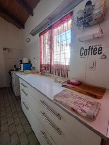 une cuisine avec un comptoir blanc et une fenêtre dans l'établissement Cómodo departamento en el bajo neuquino, à Neuquén