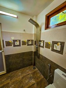 a bathroom with a shower with a toilet and a window at Wild Horizon in Udawalawe