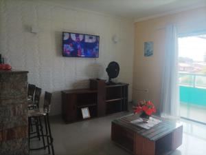 uma sala de estar com uma mesa e uma televisão na parede em Estrela de Iguaba em Iguaba Grande