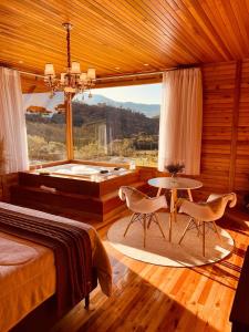 um quarto com uma cama, uma banheira e uma mesa em Refúgio Romântico com jacuzzi e café da manhã em Rancho Queimado em Rancho Queimado