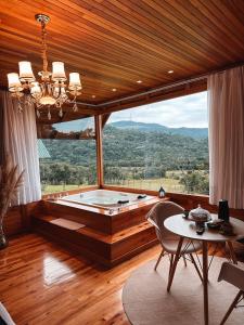 uma ampla sala de estar com uma banheira e uma mesa em Refúgio Romântico com jacuzzi e café da manhã em Rancho Queimado em Rancho Queimado
