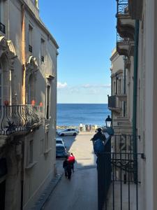 a group of people walking down a street next to the ocean at Archè in Syracuse