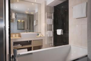 a bathroom with a bath tub and a sink at Hôtel Etoile Maillot in Paris +48 photos