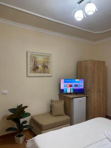 een slaapkamer met een bed, een tv en een stoel bij Aron’s House in Krujë