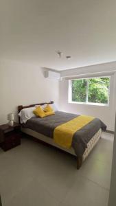 a bedroom with a bed with yellow sheets and a window at Apartamento hermoso Playa Blanca in Punta Leona