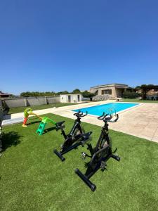 drie fietsen geparkeerd op het gras naast een zwembad bij Villa Perilli - Luxury Stay con piscina privata in Diso