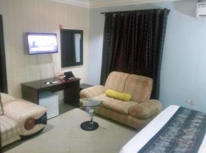een hotelkamer met een bank, een stoel en een bureau bij Petesville Hotel Limited in Calabar