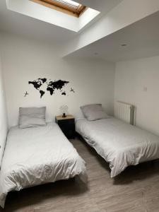 two beds in a room with white walls at Appartement au pied des cols in Saint-Jean-de-Maurienne