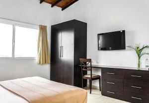 a bedroom with a bed and a desk and a tv at Hotel Kariña Maturín in Maturín