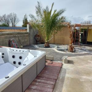 una bañera blanca en el patio trasero con una palmera en Au gué du bois, en Neuville-du-Poitou