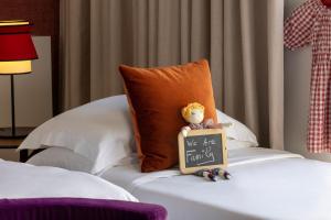 a teddy bear sitting on a bed with a we are family sign at Hôtel Etoile Maillot in Paris