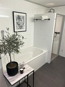 a bathroom with a tub and a potted plant on a table at Appartement ALLURE 4 Zimmer Gartenwohnung in Eschen