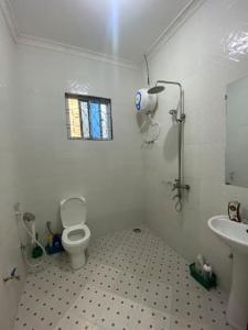 a white bathroom with a toilet and a sink at Hideaway House in Mwanza
