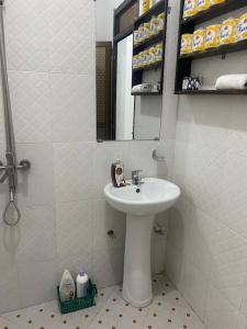Baño blanco con lavabo y espejo en Hideaway House, en Mwanza