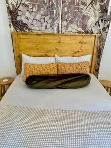 a bed with a wooden headboard and white sheets at Hideaway House in Mwanza
