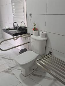 Baño blanco con aseo y lavamanos en Pousada Vila Real PG en Praia Grande