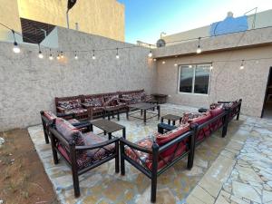 eine Terrasse mit Ledersofas, Tischen und Lampen in der Unterkunft شاليهات حائط طيني in Riad