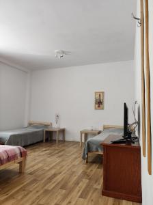 a bedroom with two beds and a desk with a television at Gościniec Biebrzański in Lipsk