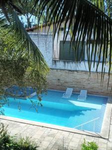 a swimming pool with two chairs and a palm tree at Casa de Praia - Maria Farinha in Paulista