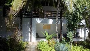 a white house with a palm tree in a garden at Casa de Praia - Maria Farinha in Paulista