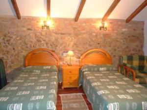 a bedroom with two beds and a stone wall at Bajo el arce del parque de Cabarceno , casa rural in Sobarzo