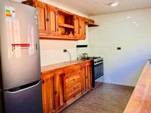 a kitchen with wooden cabinets and a stainless steel refrigerator at Cabañas en Parque Guaiquivilo con tinajas calientes in Colbún