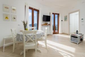 a white dining room with a table and chairs at Villa Lotos - De Vivo Realty in Massa Lubrense