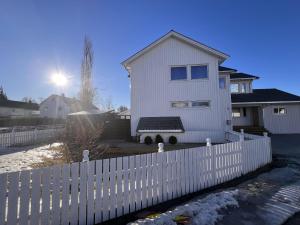 una cerca blanca frente a una casa blanca en Brand new and private studio apartment! en Bodø