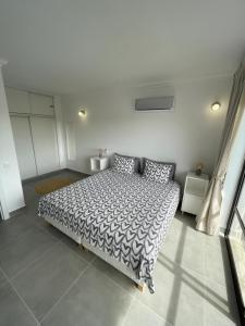 a bedroom with a bed with a black and white comforter at Elm Apartament in Sagres +15 photos