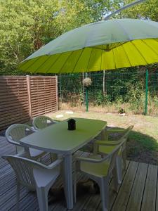 a table and chairs under an umbrella on a deck at Maison en bordure de forêt in Blanquefort