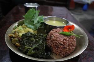 a plate of food with rice and vegetables on a table at Hasera Organic Farmstay: Farm to Table & Mountain View in Dhulikhel