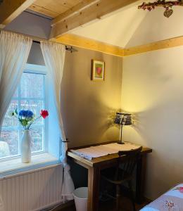 a bedroom with a desk and a window with a vase of flowers at Skrattande Ko in Tingsryd