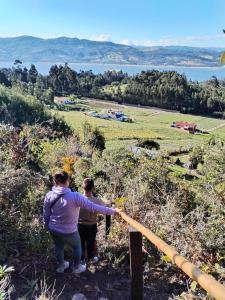 two people standing on a hill looking at the view at Cabaña Kandilejas in Guatavita +2 photos