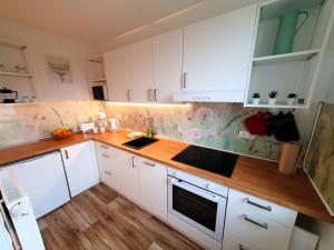 a kitchen with white cabinets and a wooden counter top at radfreundliches Wohlfühl-Apartment mit Terrasse und Parkplatz - FeWo Woody in Schwerin
