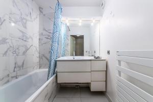a bathroom with a tub and a sink and a mirror at Grande Île - Apartment near Disneyland Paris in Meaux